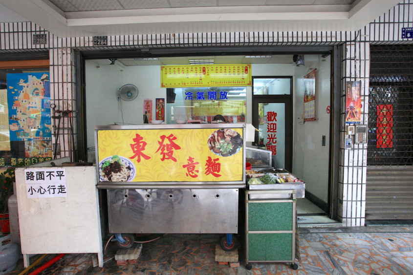 店面的骑楼摆放料理的摊位黄色的招牌写著东发意面.